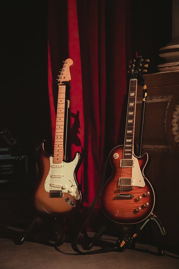 Two electric guitars on stage with dramatic red curtains in Tlaxcala, Mexico.