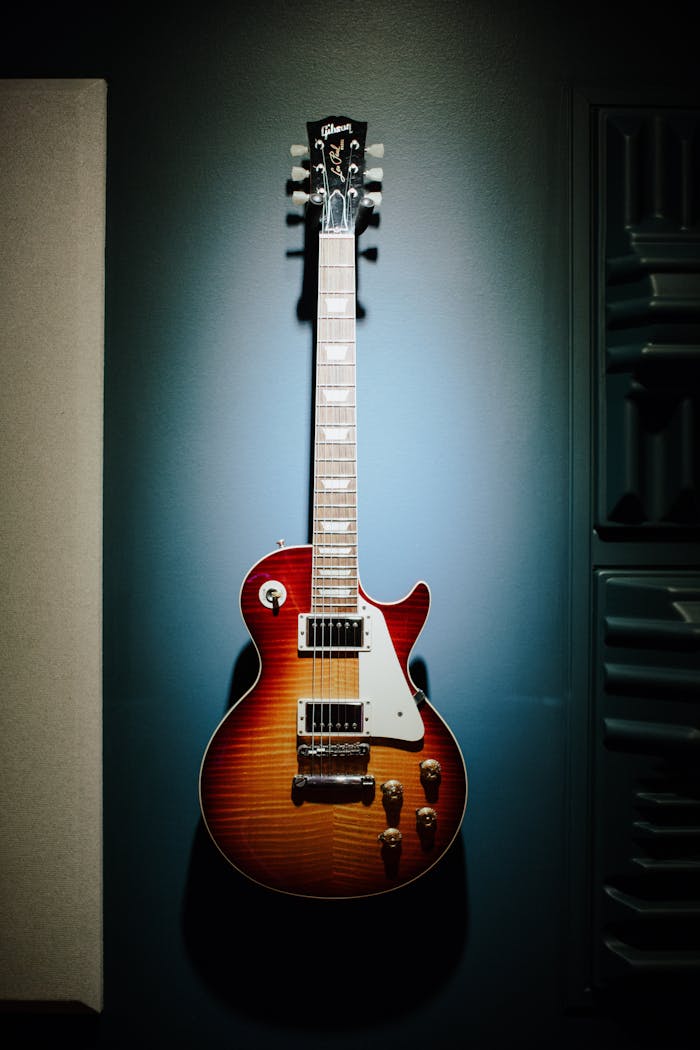 A classic sunburst electric guitar hanging in a dimly lit music studio.